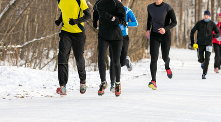 group runners participating in winter outdoor race or marathon on snow-covered trail