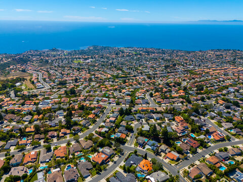 Wide-angle aerial panorama of Rancho Palos Verdes with rows of homes extending to the Pacific Ocean, under a clear blue sky on a bright and calm summer day in Southern California
