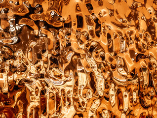 abstract, highly reflective, and metallic surface with intricate, fluid-like patterns. The surface...