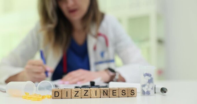 Dizziness word arranged on wooden cubes put near pill organizer and plastic tubes. Scene points to instability and need for neurological control