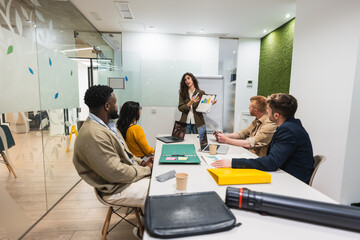 Coworkers listening to their manager explaining a project during a presentation in a coworking...