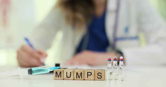 Mumps word spelled out on wooden cubes appears near syringe and vials. Vaccination tools indicate viral infection and need for children immunization