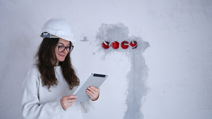Woman engineer with white helmet using tablet inspecting electrical system during building renovation