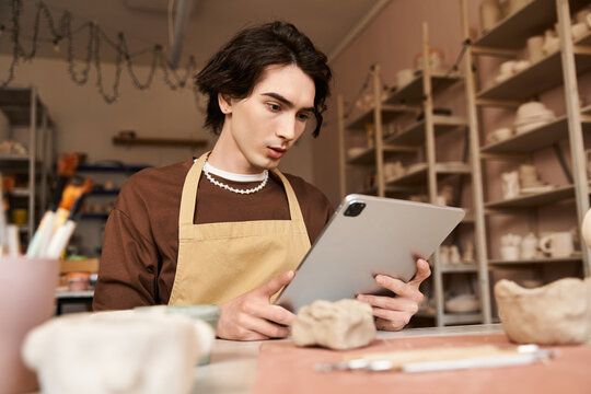 Handsome stylish man exploring pottery techniques in a creative ceramics studio setting
