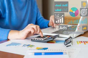 Businesswoman is working with calculator and laptop, analyzing financial kpi data and advertising analytics, focusing on sales performance and progress towards business objectives