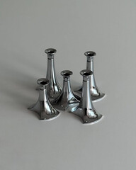 Clustered chrome candle holders on flat surface.