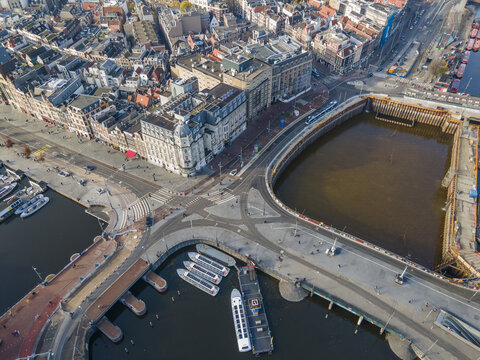 Aerial view of the vibrant city where bridges cross canals near buildings with classic architecture, creating a striking contrast of old and new, Amsterdam, North Holland, Netherlands.