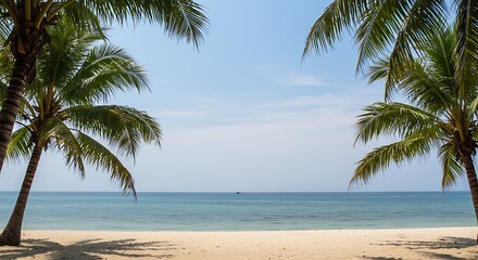Fototapeta premium Two lush palm trees frame a pristine sandy beach and the calm, clear turquoise ocean stretching to the horizon under a bright, inviting blue sky.