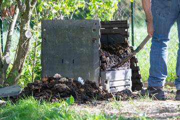 Homme avec une fourche creusant un bac à compost de jardin extérieur rempli de déchets alimentaires. Promouvoir le recyclage durable et les pratiques de compostage domestique.