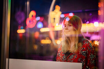Dreamy Young Woman Reflected in Colorful Neon Lights at Carnival