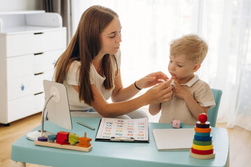 By the blue table. Speech therapist is with young boy indoors