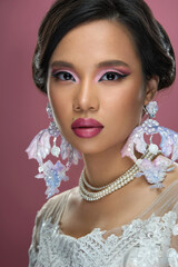 Close-up portrait of a beautiful brunette Asian woman with exquisite makeup in a white wedding...