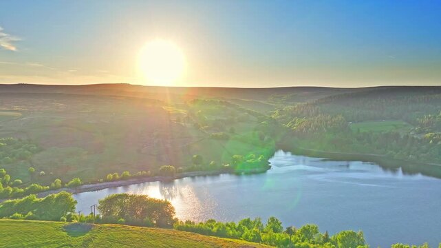 Aerial: Strines Reservoir, water storage reservoir, with forest at sunset near Sheffield, South Yorkshire, England, pull out drone shot