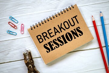 BREAKOUT SESSIONS on a notebook. colored pencils with a wooden table background.