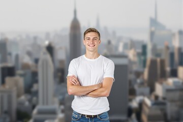 Fototapeta premium Confident young man with arms crossed against a cityscape backdrop.