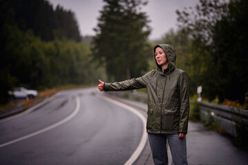 Smiling Woman Hitchhiking in the Rain on Forest Road