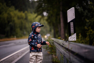 Curious Boy Observes Road Sign on a Rainy Day