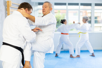 Intense oriental fight session, senior athletics practice combat judo techniques with male teacher,...