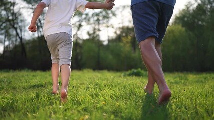 Two young boys running through a field. A father and child are walking in the grass. Family walking off in the park. Two young boys sprinting across a lifestyle meadow.
