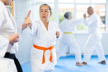 Irate mature female karate practitioner fighting with her opponent in sports hall