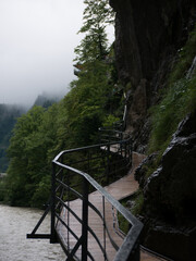 Steg entlang nebelverhangenem Felsen im Gebirge