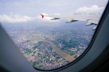 wing of an airplane flying above clouds, viewed from the passenger window. There are many white...