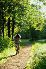 girl riding a bicycle in park. summer activities holiday, Cycling season. Active leisure outdoor in woodland. Daily active lifestyle. back view