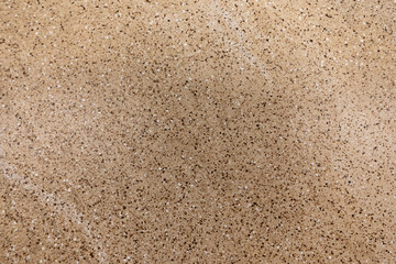 Textured surface displaying fine grains and speckles resembling natural stone formations in soft brown tones