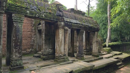 Ta Prohm, Cambodia - 3 July 2025. Moss-streaked pillars support a weathered stone corridor in Ta...