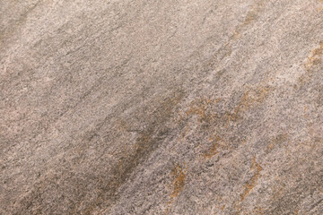 Textured surface of natural stone with subtle color variations observed in natural light