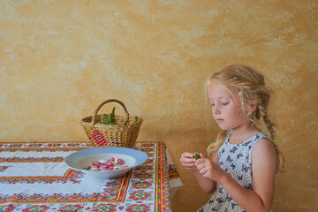 little girl peels beans, hands of a child cleans bean pods at the table