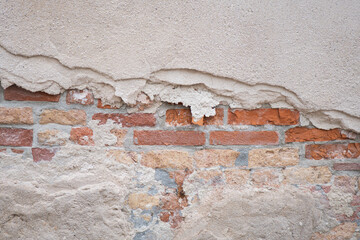 Weathered wall revealing old bricks and plaster in an urban setting