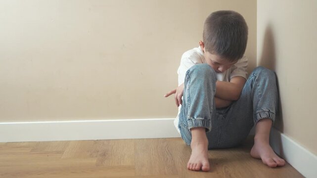 Young girl sitting on the floor. Sad child sits on a lifestyle corner and is punished. A teenage girl is traumatized by a violent incident. A little girl sitting on the ground.