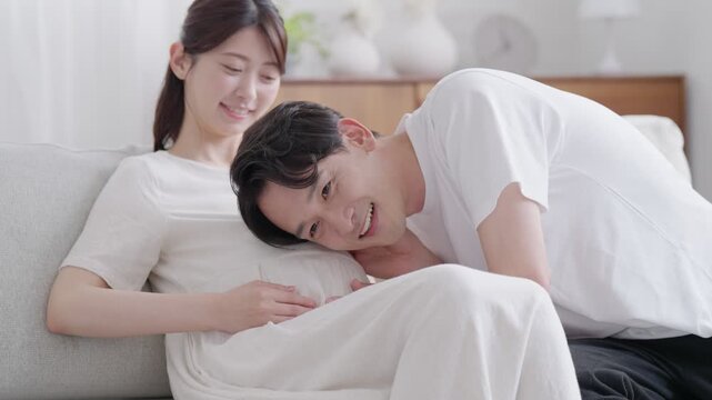 妊婦のお腹の赤ちゃんに話すパパ