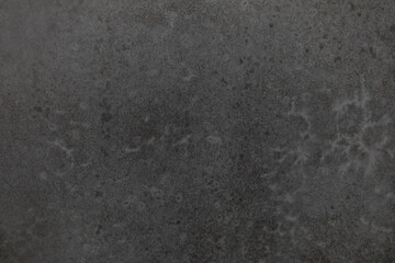 Dark textured surface with subtle patterns highlighting natural variations and depth in design