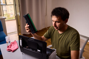 A person meticulously assembling a printer within a brightly lit and organized workspace