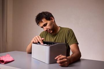 A focused man cleaning a device with a cloth for proper maintenance and cleanliness