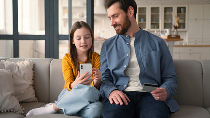 Glad Caucasian father male guy looking screen mobile phone kid little girl scrolling smartphone at...
