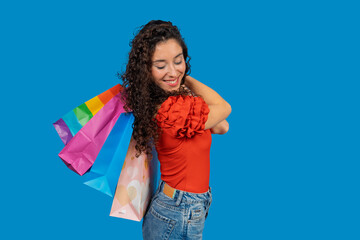 Happy shopper holding colorful shopping bags on blue background
