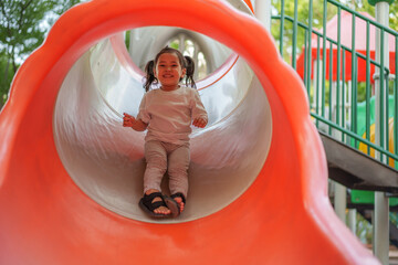 happy toddler baby girl sliding and playing at playground