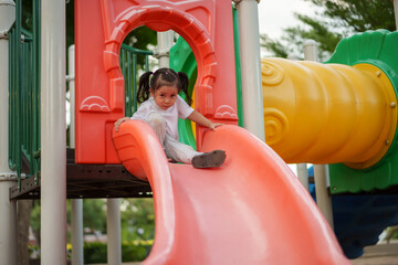 happy toddler baby girl sliding and playing at playground