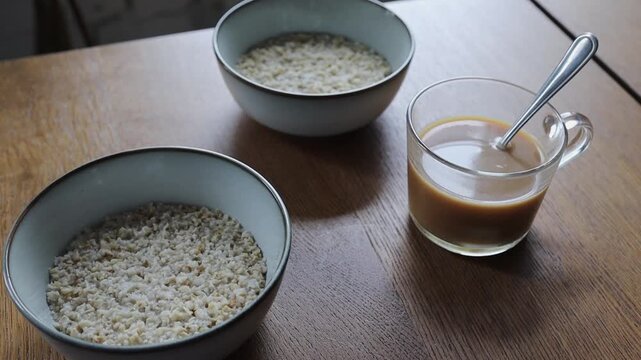 Two bowls of oatmeal with a cup of coffee on a minimalist breakfast table. Simple, healthy morning meal, frugal, frugal breakfast