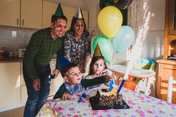 Family celebrating child's birthday with cake and fireworks