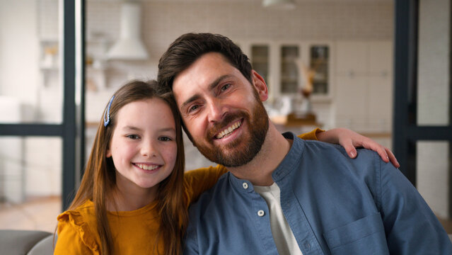 Happy carefree family portrait Caucasian child little girl kid daughter hugging cuddle touch dad adult man male father parent guy daddy smile with dental white teeth at home mortgage custody parenting