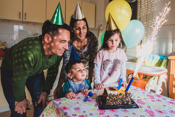 Family celebrating kid's birthday with cake and fireworks