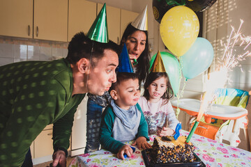 Family blowing out candles on birthday cake with sparkler