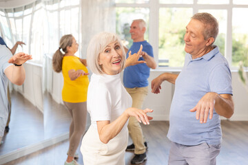 Couple of elderly man and elderly woman dancing twist in studio