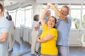 Elderly man and elderly woman dance ballroom dance waltz in studio