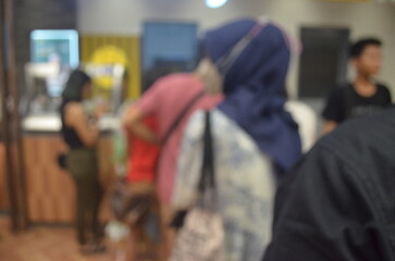 A dreamy blurred photo of people queuing to buy food, featuring soft lights and indistinct figures,...
