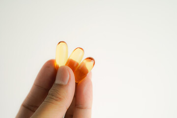 Male hand holding Fish oil capsules with omega 3, omega 9, vitamin D, vitamin E, Cod liver oil